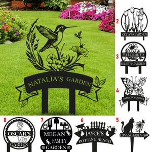May include: A black metal garden stake featuring a hummingbird and floral design with a banner reading NATALIA'S GARDEN. Additional designs include various personalized garden signs with motifs like butterflies, flowers, cats, and gardening tools.