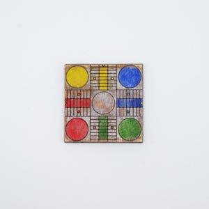 May include: A square wooden game board with a grid pattern. The board features colored circles in yellow, blue, red, and green, with corresponding colored bars. The board is set against a white background.