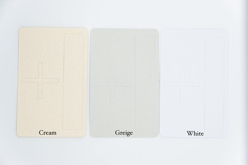 May include: Three rectangular cards with rounded corners, each featuring a debossed plus sign and a vertical rectangle outline. The cards are displayed in cream, greige, and white, with the corresponding color names printed below each card.