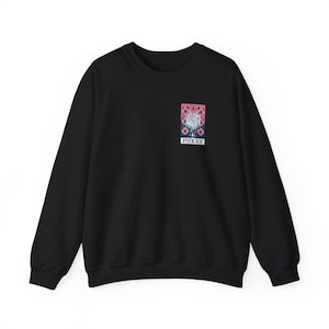 Peut inclure: Sweat-shirt noir avec un petit motif rectangulaire sur la poitrine. Le motif présente un design rose et bleu avec les mots "FUCK ICE" en lettres blanches. Le sweat-shirt a des manches longues et un col rond.