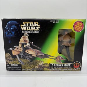 Op de afbeelding: Een Star Wars "The Power of the Force" actiefiguurset met een Speeder Bike met Luke Skywalker in Endor-uitrusting. De doos bevat een afbeelding van Darth Vader en een Luke Skywalker-figuur. De doos leest "Bike explodes apart and ejects Luke!"
