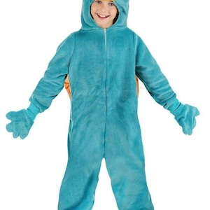 May include: A child in a teal plush Perry the Platypus costume, complete with a brown fedora hat. The costume includes a hood with a yellow beak and eyes, matching gloves, and yellow feet. The child is smiling.