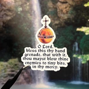 May include: A sticker featuring a golden orb with a cross on top, adorned with jewels. The sticker has the text "O Lord, bless this thy hand grenade, that with it, thou mayst blow thine enemies to tiny bits, in thy mercy."