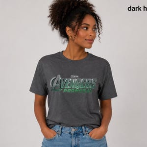 K&ouml;nnte beinhalten: Ein dunkelgrau meliertes Kurzarm-T-Shirt mit dem silber-gr&uuml;nen Avengers-Logo und dem Schriftzug Marvel Studios Avengers Doomsday auf der Brust. Das T-Shirt hat einen Rundhalsausschnitt und eine normale Passform.