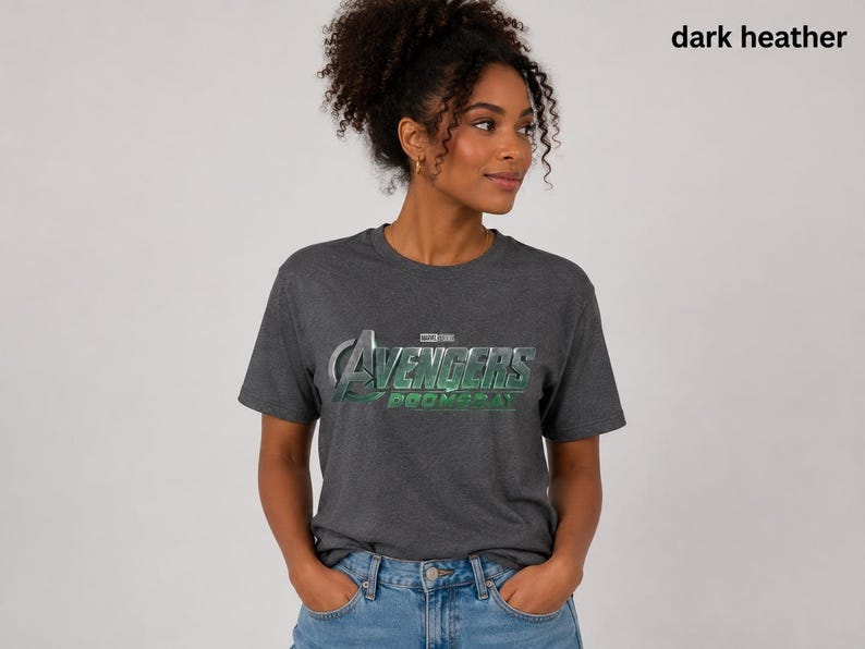K&ouml;nnte beinhalten: Ein dunkelgrau meliertes Kurzarm-T-Shirt mit dem silber-gr&uuml;nen Avengers-Logo und dem Schriftzug Marvel Studios Avengers Doomsday auf der Brust. Das T-Shirt hat einen Rundhalsausschnitt und eine normale Passform.