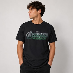 K&ouml;nnte beinhalten: Ein schwarzes kurz&auml;rmeliges T-Shirt mit einem Grafikdruck auf der Brust, der den Text Avengers Doomsday in einer metallisch silbernen und gr&uuml;nen Schrift zeigt. Das T-Shirt hat einen Rundhalsausschnitt und eine Standardpassform, mit dem Wort black.