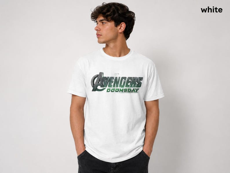 K&ouml;nnte beinhalten: Ein wei&szlig;es T-Shirt mit kurzen &Auml;rmeln und dem auf die Brust gedruckten Avengers Doomsday-Logo. Die Grafik zeigt das ikonische Avengers A-Symbol in metallischer Optik mit gr&uuml;nen Akzenten sowie den Schriftzug Doomsday in Fettdruck.