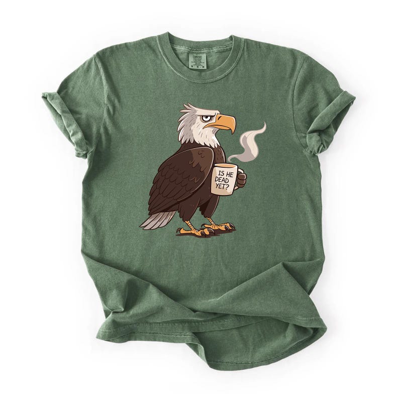Puede incluir: Camiseta verde con una ilustraci&oacute;n de un &aacute;guila de dibujos animados. El &aacute;guila tiene la cabeza blanca, el cuerpo marr&oacute;n y el pico y las patas amarillas. Sostiene una taza con el texto "IS HE DEAD YET?" y vapor saliendo. La camiseta tiene las mangas enrolladas.