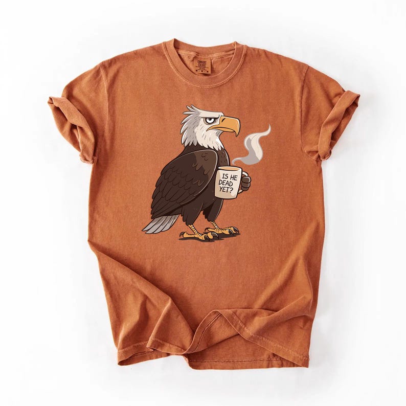 Puede incluir: Camiseta naranja quemado con un &aacute;guila de dibujos animados sosteniendo una taza de caf&eacute;. El &aacute;guila tiene plumas blancas y marrones y un pico amarillo. La taza tiene el texto "IS HE DEAD YET?". La camiseta tiene las mangas enrolladas.