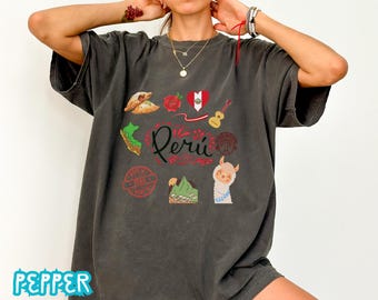 May include: Dark gray t-shirt with a graphic design featuring Peruvian cultural symbols. The design includes a map of Peru, a heart with the Peruvian flag, a guitar, a llama, and the word "Perú" in red script.