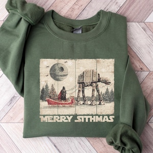 May include: Green sweatshirt with a festive Star Wars graphic. The design includes an AT-AT walker, a Death Star, and a figure in a sleigh. The text "MERRY SITHMAS" is printed below the image.