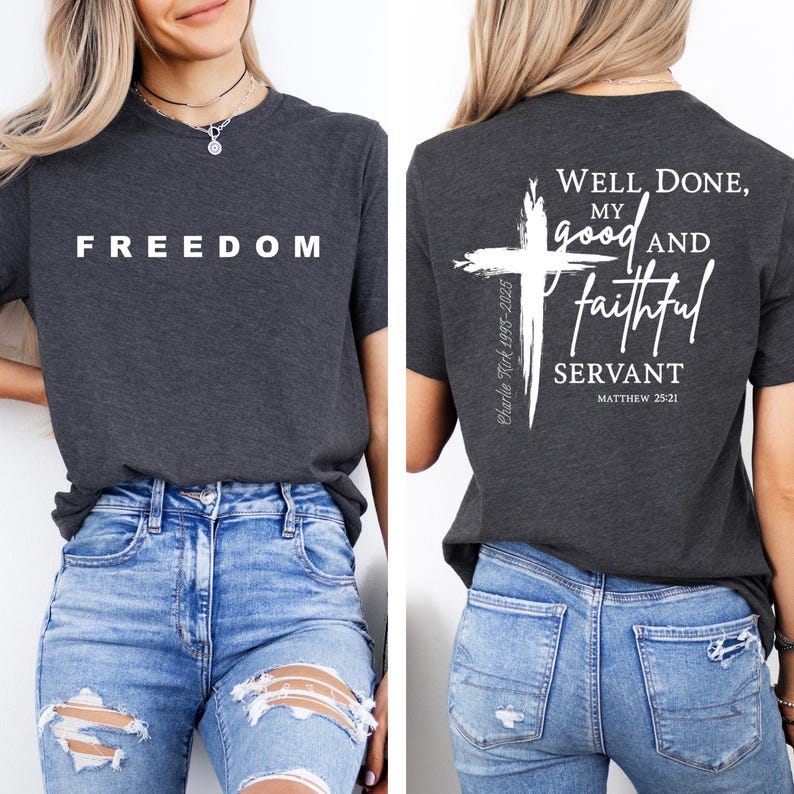 May include: A charcoal grey t-shirt with the word "FREEDOM" printed in white on the front. The back of the shirt displays a white cross graphic and the text "Well Done, My Good and Faithful Servant" and "Matthew 25:21".