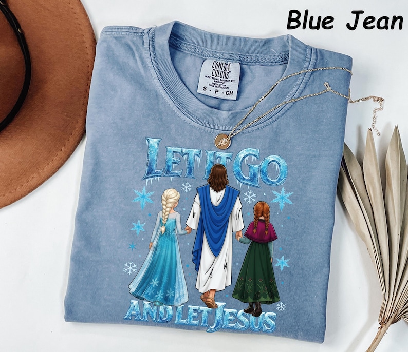 May include: A light blue Comfort Colors t-shirt with the text "LET IT GO AND LET JESUS" and a graphic of Jesus with two characters from the movie Frozen. A gold necklace is draped across the shirt.