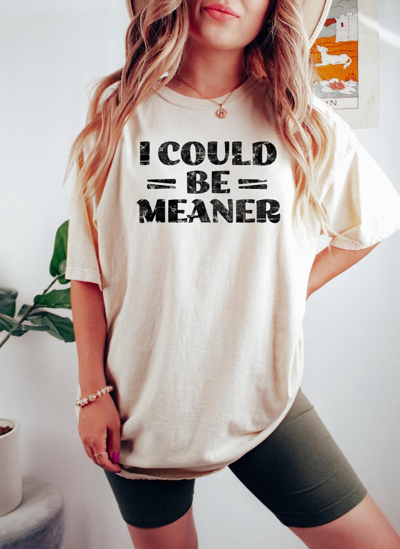 May include: A white t-shirt with black text that reads "I could = be = meaner".