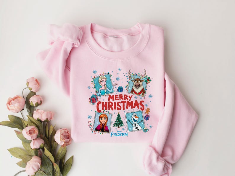 Puede incluir: Sudadera rosa claro con personajes de la pel&iacute;cula Frozen. El dise&ntilde;o incluye a Elsa, Anna, Kristoff y Olaf, con las palabras "Merry Christmas" y un &aacute;rbol de Navidad. Un art&iacute;culo festivo para las fiestas.