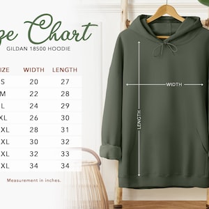 K&ouml;nnte beinhalten: Ein olivgr&uuml;ner Gildan 18500 Hoodie, der auf einem Holzkleiderb&uuml;gel pr&auml;sentiert wird. Das Bild enth&auml;lt eine Gr&ouml;&szlig;entabelle mit Ma&szlig;en in Zentimetern: S (51 cm Breite, 69 cm L&auml;nge), M (56 cm Breite, 71 cm L&auml;nge), L (61 cm Breite, 74 cm L&auml;nge), XL (66 cm Breite, 76 cm L&auml;nge), 2XL (71 cm Breite, 79 cm L&auml;nge), 3XL (76 cm Breite, 81 cm L&auml;nge), 4XL (81 cm Breite, 84 cm L&auml;nge) und 5XL (86 cm Breite, 86 cm L&auml;nge).