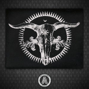May include: Black and white patch with a skull of a bull in a circle with a sunburst design. The bull skull has a star in the center of its forehead and a crescent moon above it.