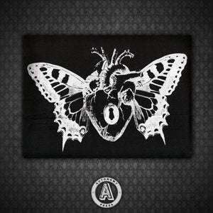 May include: Black and white graphic print of a human heart with a keyhole, surrounded by butterfly wings. The image is on a black fabric background.