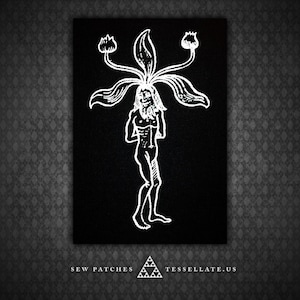 May include: White embroidered patch on black fabric depicting a humanoid figure with a plant growing from its head. The plant has three flowers. The text "SEW PATCHES" and "TESSELATE.US" is at the bottom of the patch.