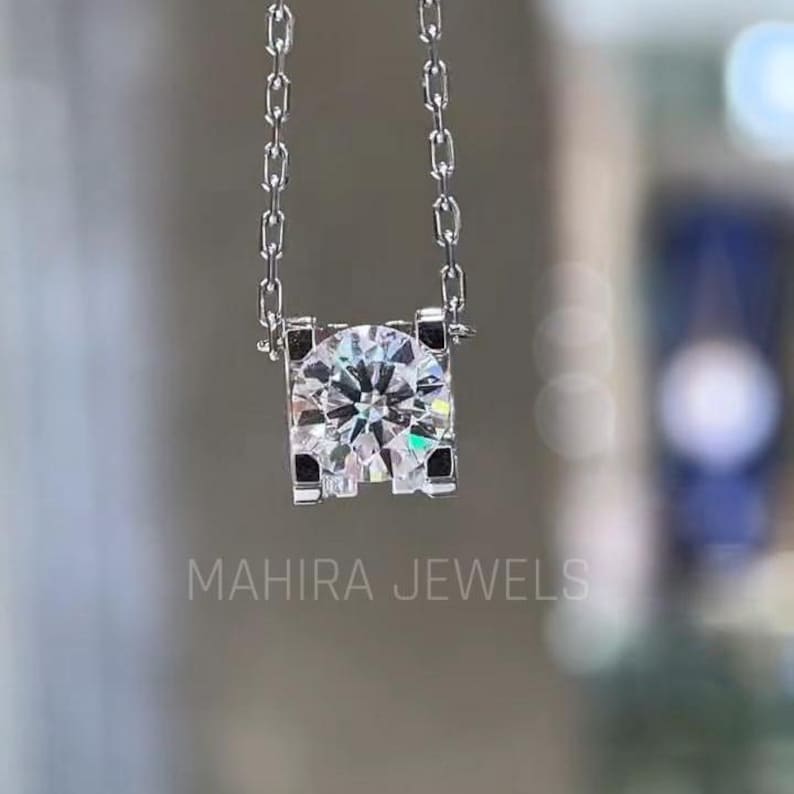 May include: A silver chain necklace with a square pendant featuring a large, clear round gemstone.