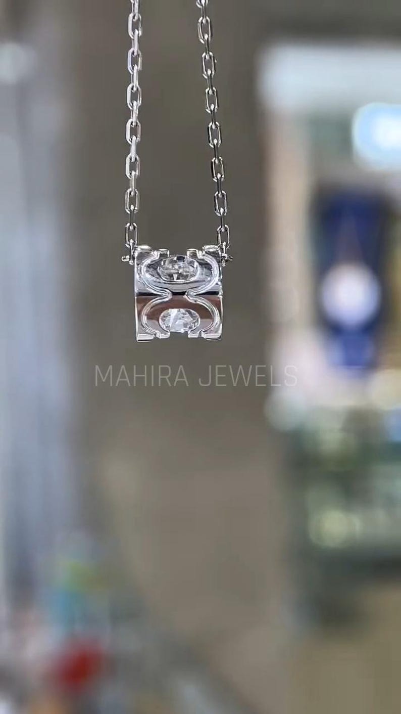 Puede incluir: Un collar de cadena de plata con un colgante de plata que presenta un dise&ntilde;o geom&eacute;trico con un cristal transparente en el centro. El colgante tiene forma de anillo con una abertura cuadrada. El collar est&aacute; colgado sobre un fondo blanco.