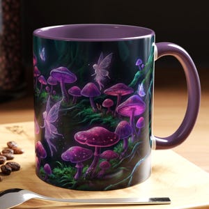 May include: A ceramic mug with a purple interior and handle. The exterior features a fantasy scene with purple mushrooms, fairies, and butterflies. The mug sits on a wooden surface with a spoon, a macaron, and coffee beans.