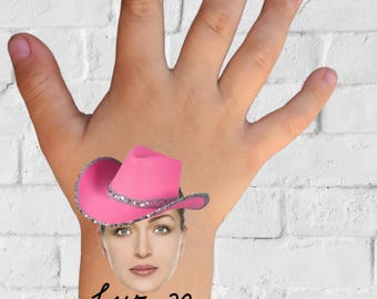 May include: A pink temporary tattoo showing a woman's face wearing a pink cowboy hat with silver trim. The tattoo includes the name "Luz" and the number "30" in cursive, and the word "TATTOO" in a pink cloud-shaped banner.