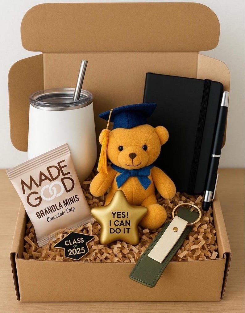 May include: A brown cardboard box filled with graduation gifts. The gifts include a white tumbler with a straw, a teddy bear wearing a blue graduation cap, a gold star with the text "YES! I CAN DO IT", a small bag of chocolate chip granola, a black notebook with a pen, a keychain with a green and white strap, and a gold pin with the text "CLASS OF 2025".