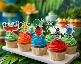 May include: A collection of cupcakes with colorful frosting, including green, orange, red, and blue. Each cupcake is topped with a decorative insect-themed cutout, such as a butterfly, ladybug, and bee. The cupcakes are arranged on a white rectangular tray.