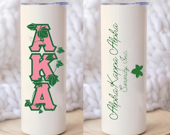 Könnte beinhalten: Weißer Isolierbecher mit den Buchstaben "AKA" in Rosa und grünen Efeu-Akzenten. Die andere Seite zeigt "Alpha Kappa Alpha Sorority, Inc." in grüner Schrift mit einem grünen Blatt.