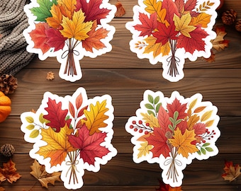 May include: Four die-cut stickers featuring bouquets of autumn leaves in shades of red, orange, yellow, and green. Each bouquet is tied with a brown ribbon. The stickers are arranged on a wooden surface with fall-themed decorations.