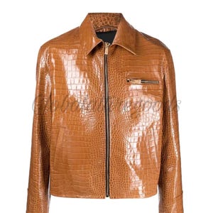 Puede incluir: Chaqueta marrón de piel sintética con textura de piel de cocodrilo. La chaqueta tiene cuello, cierre de cremallera y un pequeño bolsillo con cremallera en el pecho. Las mangas tienen puños abotonados.
