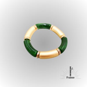 Pode incluir: Um bracelete de estilo bambu verde e dourado. O bracelete é feito de contas redondas com um acento de metal dourado.