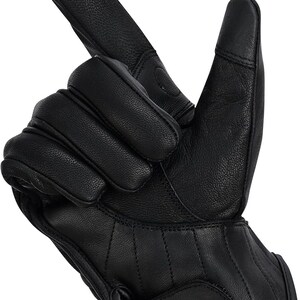 May include: Black leather motorcycle gloves with a textured finish. The gloves have reinforced knuckle padding and a Velcro strap closure. The index finger and thumb are designed for touchscreen use.