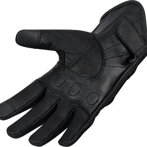 May include: Black leather motorcycle glove with reinforced knuckles and a wrist strap. The glove features a textured surface and is designed for protection and grip. The fingers have a touch-sensitive tip for use with smartphones.