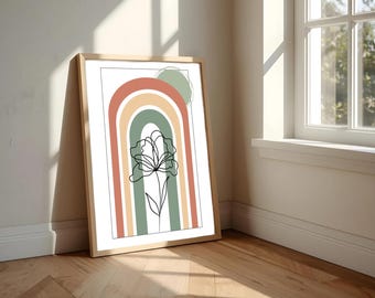 Op de afbeelding: Een ingelijste kunstdruk met een minimalistisch bloemendesign. Het kunstwerk toont een zwarte lijntekening van een bloem over een regenboogboog in gedempte kleuren van oranje, groen en geel. De print wordt op een houten vloer weergegeven.