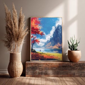May include: A framed landscape art print featuring a vibrant autumn scene. A red-leafed tree stands near a lake, with mountains in the background under a blue sky with clouds. The artwork is displayed on a wooden surface.