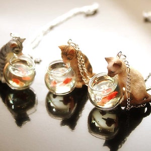 Cat is looking at goldfish in a fish bowl necklace