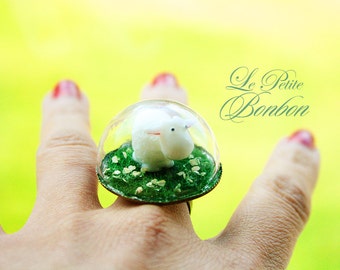 Little sheep is inside the dome playing on the grass glass globe ring