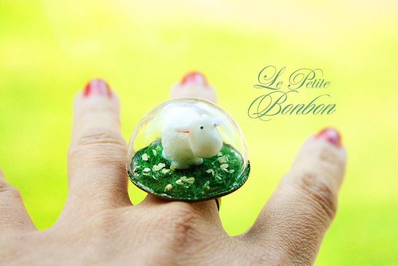 Little sheep is inside the dome playing on the grass glass globe ring image 1