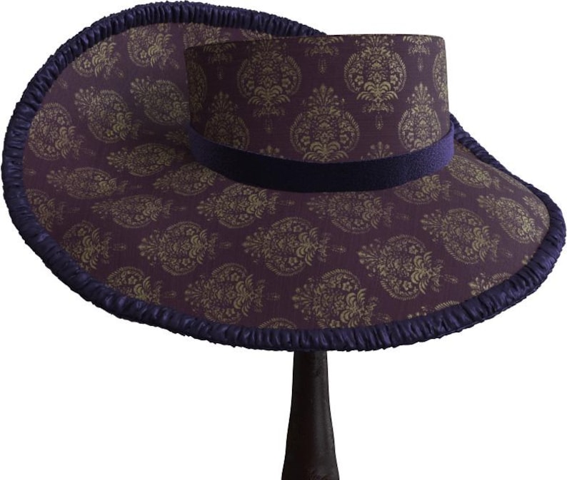 May include: A wide-brimmed hat with a purple and gold paisley pattern. The hat has a dark purple velvet band and a ruffled edge.