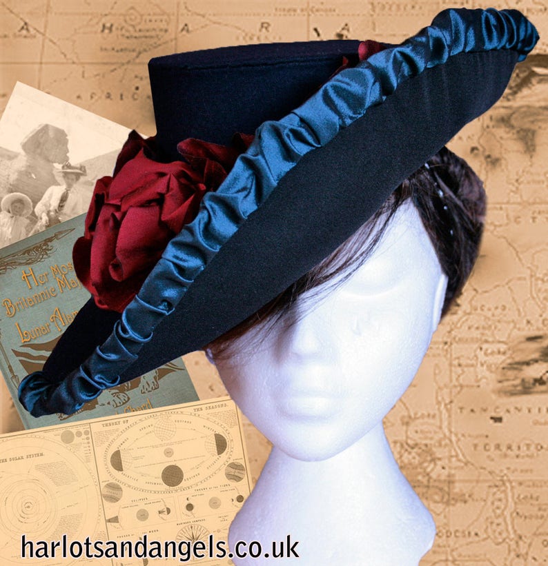 May include: A black felt hat with a wide brim and a teal blue ribbon. The hat is decorated with a large red rose.