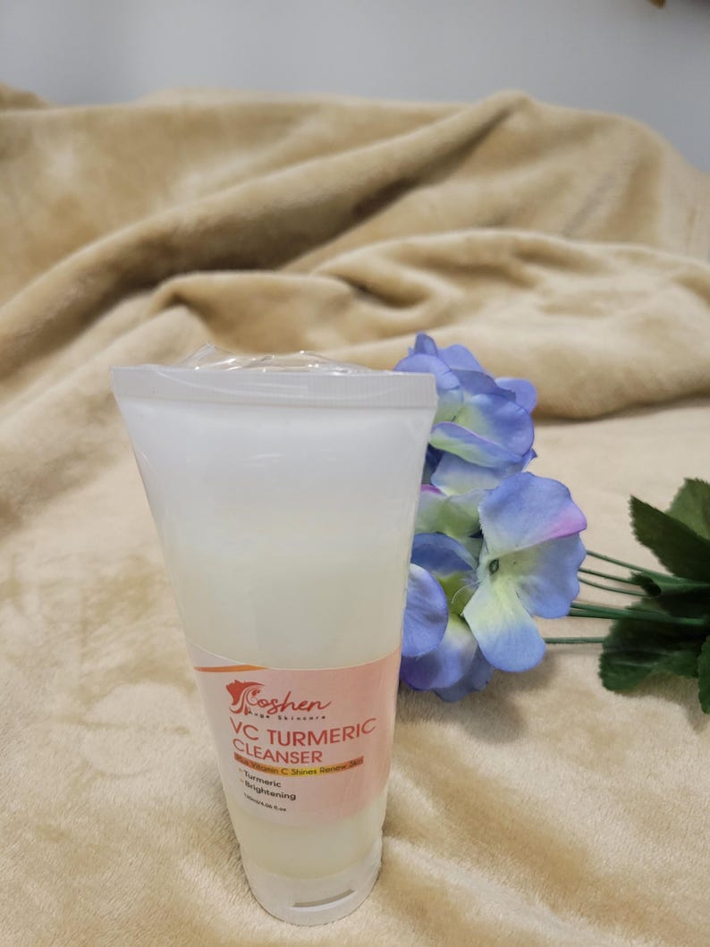 May include: A white plastic tube of VC Turmeric Cleanser with a pink and orange label. The label says "Coshen Pure Skincare" and "VC Turmeric Cleanser". The label also says "Turmeric Brightening" and "Vitamin C Serum Boost".
