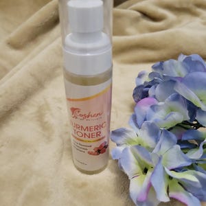 May include: A clear plastic bottle with a white pump dispenser containing a yellow liquid. The bottle is labeled "Koshen Naturals Turmeric Toner" and lists benefits such as "Acne Removal, Moisturizes, Brightens".