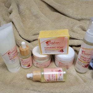 May include: A set of turmeric skincare products from Koshen, including a cleanser, serum, toner, soap, and essential oil. The products are packaged in white and yellow bottles with pink and white labels.