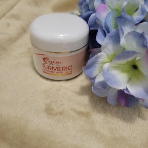 May include: A white jar with a gold lid and a pink label that says "Koshen Skin Care" and "Turmeric & Ascorbic Acid".