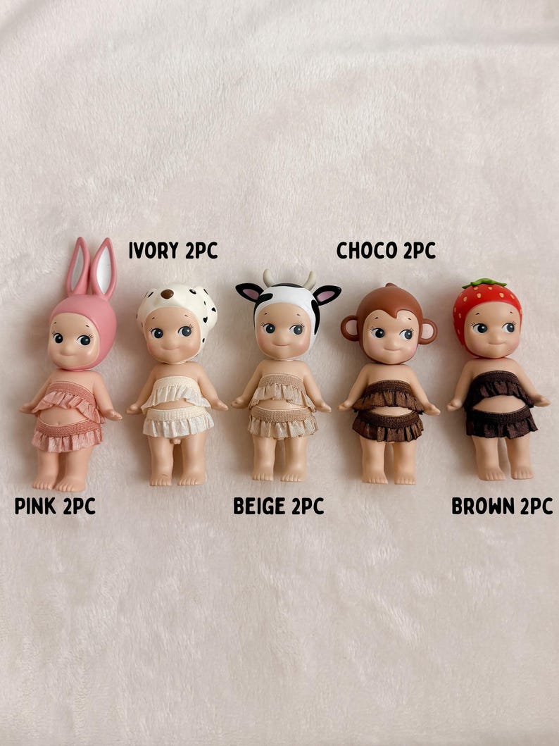 Puede incluir: Cinco peque&ntilde;as figuras con sombreros y trajes con tem&aacute;tica de animales. Las figuras son de color rosa, marfil, beige, marr&oacute;n y chocolate. Cada figura tiene una parte superior e inferior con volantes. El texto de la imagen dice "PINK 2PC", "IVORY 2PC", "BEIGE 2PC", "CHOC 2PC" y "BROWN 2PC".