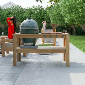 May include: A green ceramic grill sits on a wooden outdoor kitchen island. The island has a lower shelf and decorative metal accents. The scene is set outdoors with a pool and lush greenery in the background.