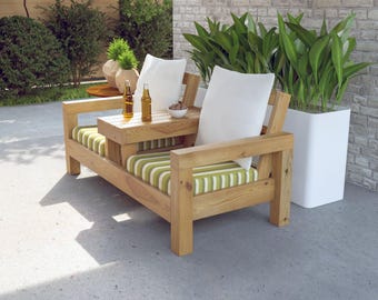 May include: Wooden outdoor loveseat with a built-in side table. The cushions have a green and white striped pattern, and white pillows are on the backrests. Two bottles and a bowl of snacks sit on the table. A white planter with green plants is to the right.