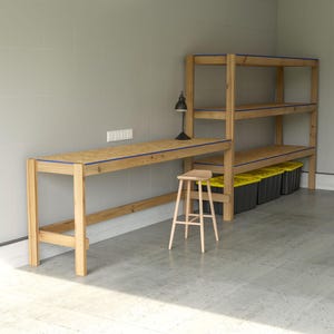 May include: A wooden workbench and shelving unit with blue trim. A small wooden stool and a black desk lamp are next to the workbench. The shelving unit has three shelves and is filled with black storage bins with yellow lids.